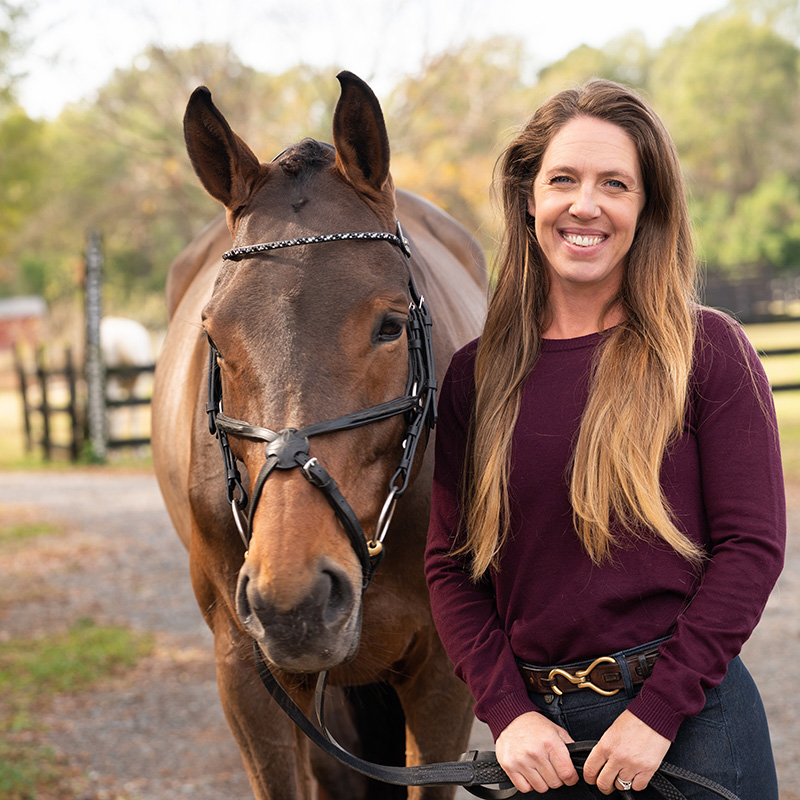 Doretta Wright, owner of Wright Nutrition, smiling at the camera standing next to a horse.